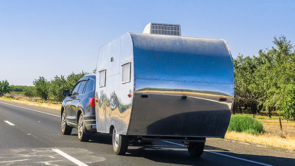 An SUV towing a silver trailer on a highway