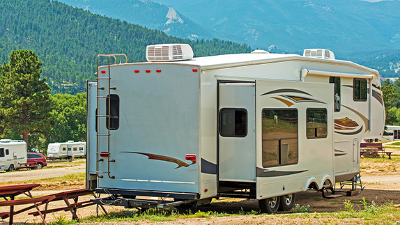 Parked fifth-wheel RV trailer in mountain campground.